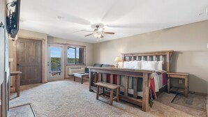A bedroom with a wooden bed, a ceiling fan, a bench, and a view of the outdoors. - Studio Lake Condo, Resort Perks, Golf and Ticket Discounts (Branson)