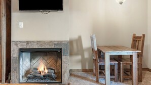 A living room with a fireplace, a television mounted on the wall, and a dining table with chairs. - Studio Lake Condo, Resort Perks, Golf and Ticket Discounts (Branson)
