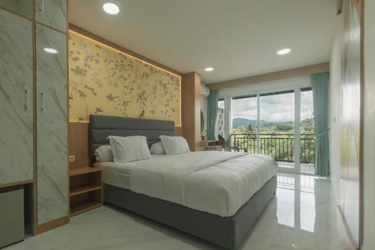 A bedroom with a large bed, a nightstand, a wardrobe, and a balcony with a view.