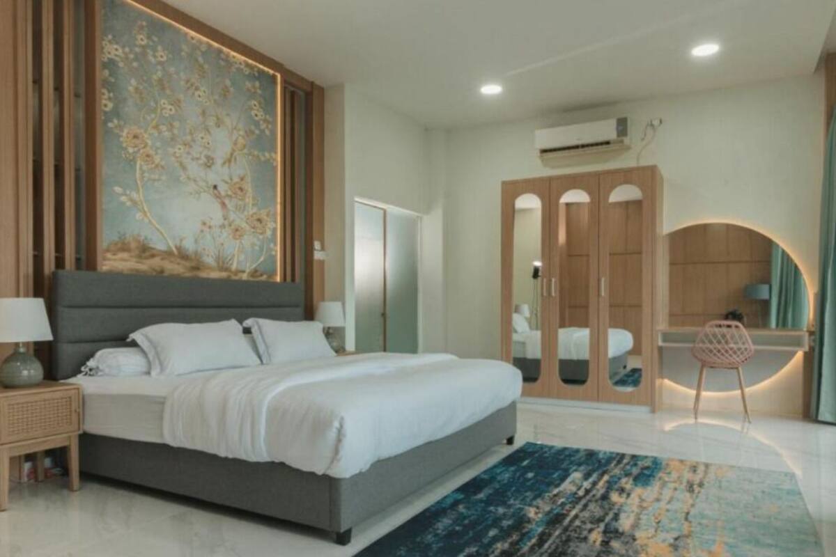 A modern bedroom with a large bed, a side table, a mirror, and a wardrobe.