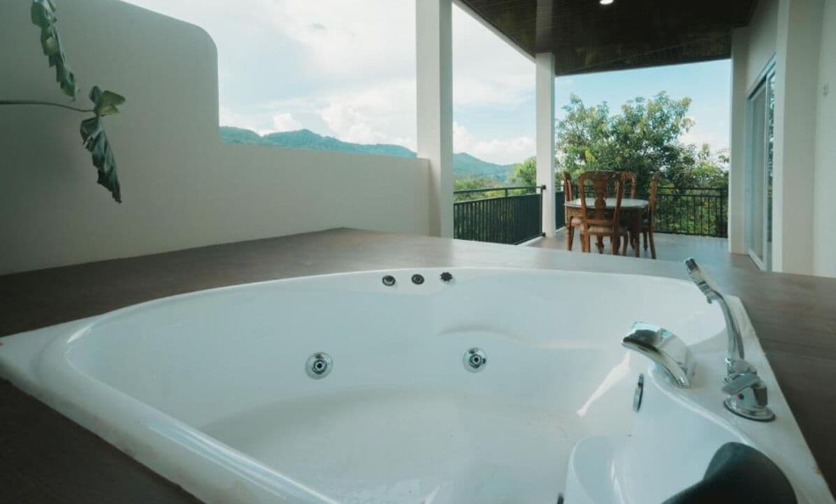 Um banheiro moderno com uma banheira grande, área de chuveiro e vista para o exterior.