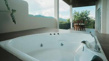 Um banheiro moderno com uma banheira grande, área de chuveiro e vista para o exterior.