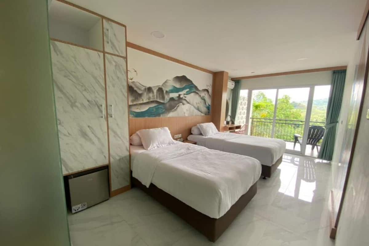 A hotel room with two beds, a marble wall, a painting, and a balcony with a view.