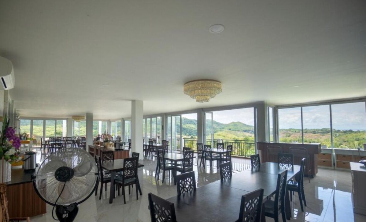 Un comedor espacioso con techos altos y grandes ventanales que ofrecen vistas a las colinas.