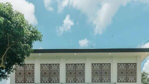 Ein modernes Gebäude mit großen Fenstern und einem Tennisplatz davor.