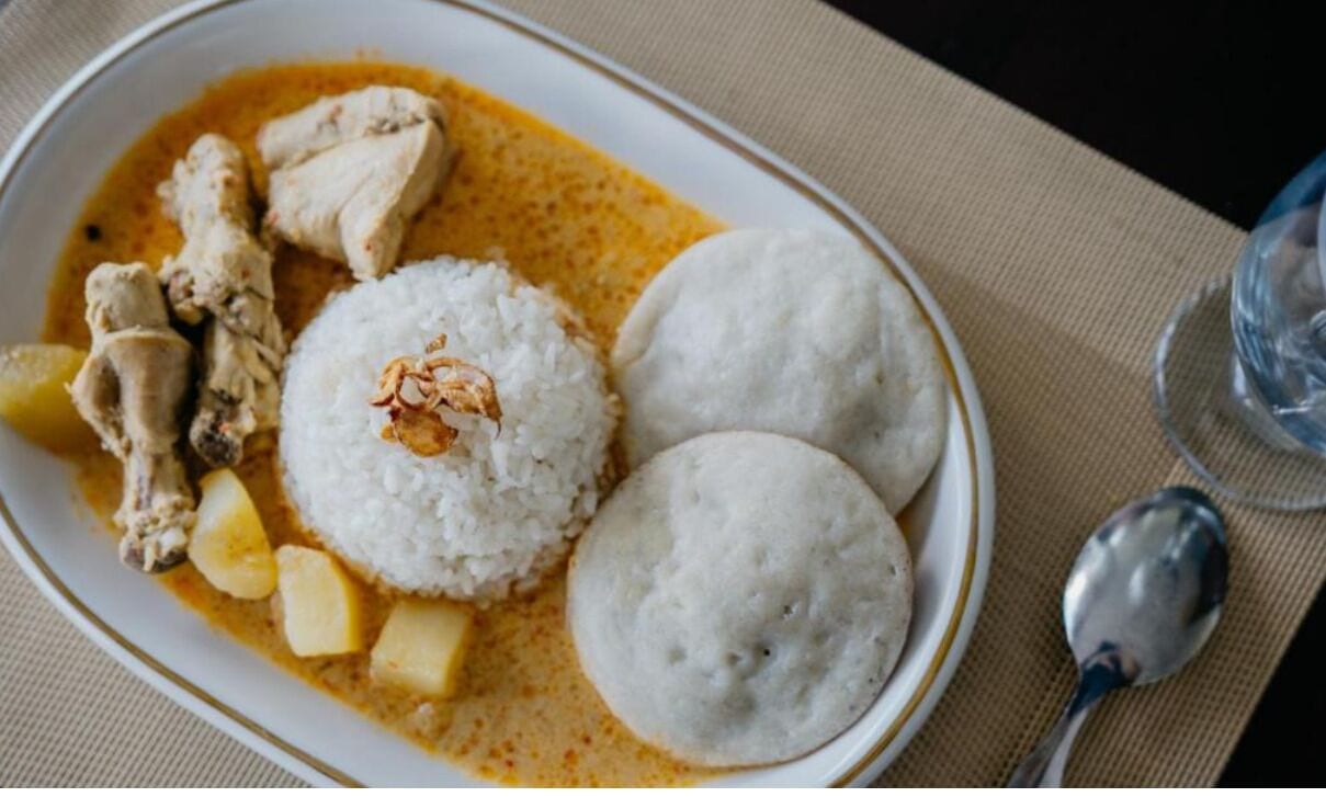 En tallerken med mad, ris, kylling og to dumplings på et bord.