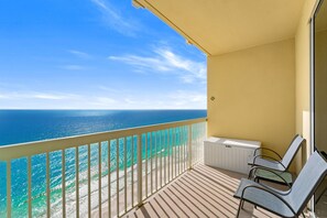 Un balcon avec vue sur l’océan, un radiateur blanc et deux fauteuils de relaxation.