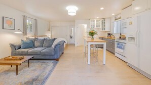 A modern kitchen with white cabinets, a dining table, and a built-in oven.