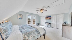 Une chambre à coucher comprenant un lit, un ventilateur de plafond, un bureau et une armoire.