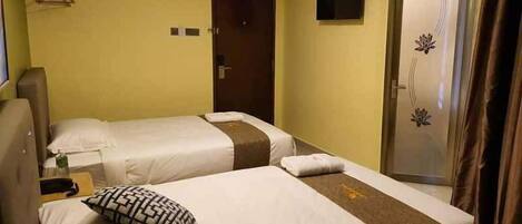 A hotel room with two beds, a wardrobe, a TV, and a door with a decorative panel.