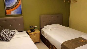 A hotel room with two beds, a nightstand with a phone and toiletries, and a painting on the wall.