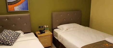 Habitación de hotel con dos camas, una mesita de noche con teléfono y artículos de aseo, y un cuadro en la pared.