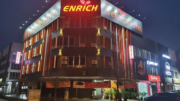 Ένα ξενοδοχείο με το όνομα ENRICH HOTEL, με μια μοντέρνα πρόσοψη, πολλά μπαλκόνια και μια επιβλητική επιγραφή.