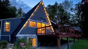 A house with a sloped roof, a deck, and a garden with flowers.
