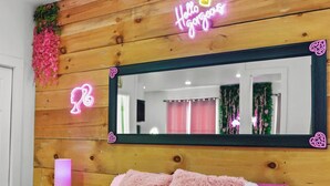 Une chambre à coucher avec une tête de lit en bois, un grand miroir et une literie rose.