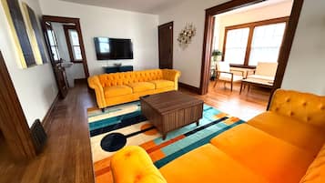 Una sala de estar con un sofá amarillo, una mesa de centro marrón y una alfombra colorida.