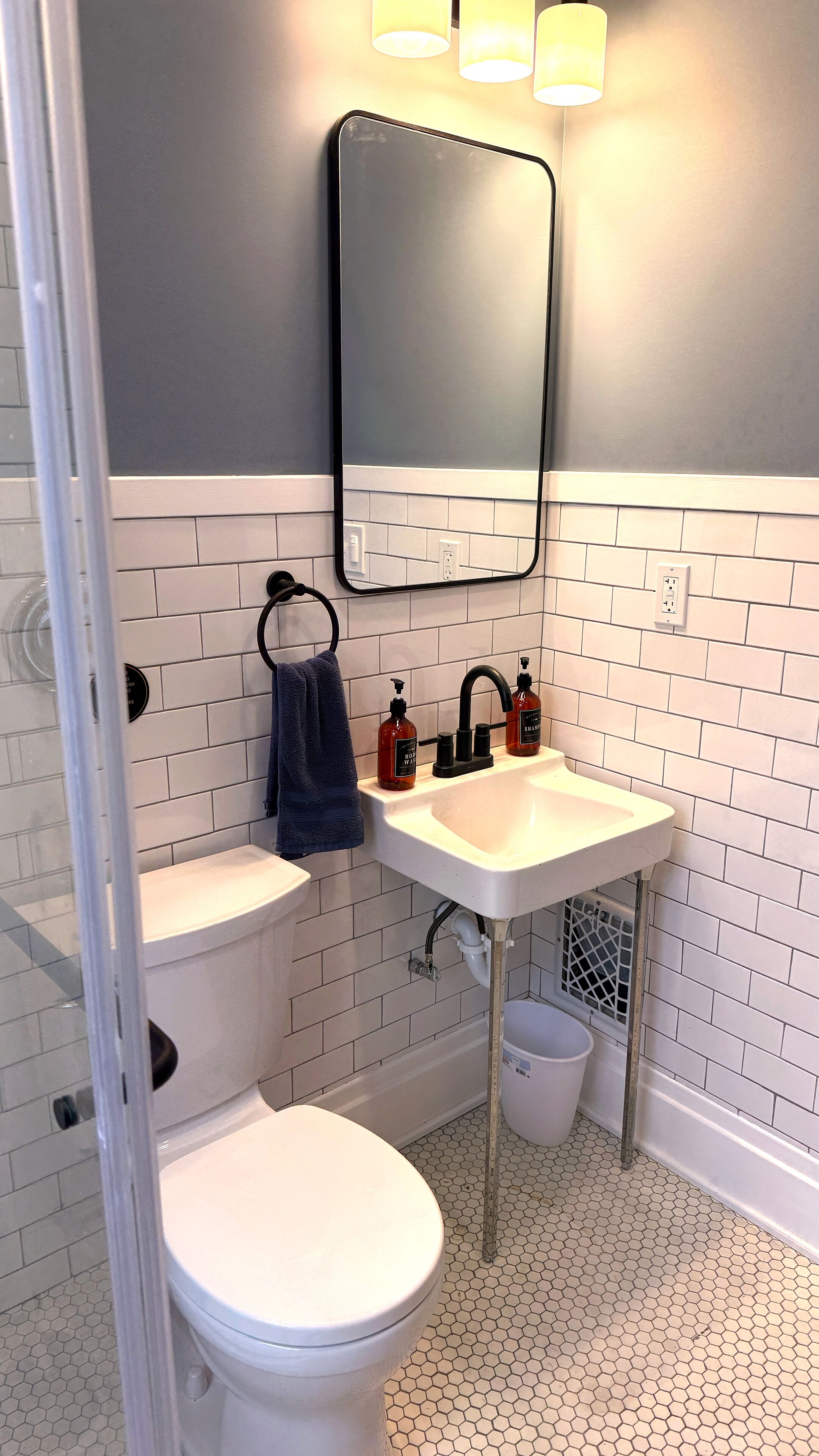 Un baño con inodoro blanco, un lavabo con espejo y una toalla colgada en la pared.
