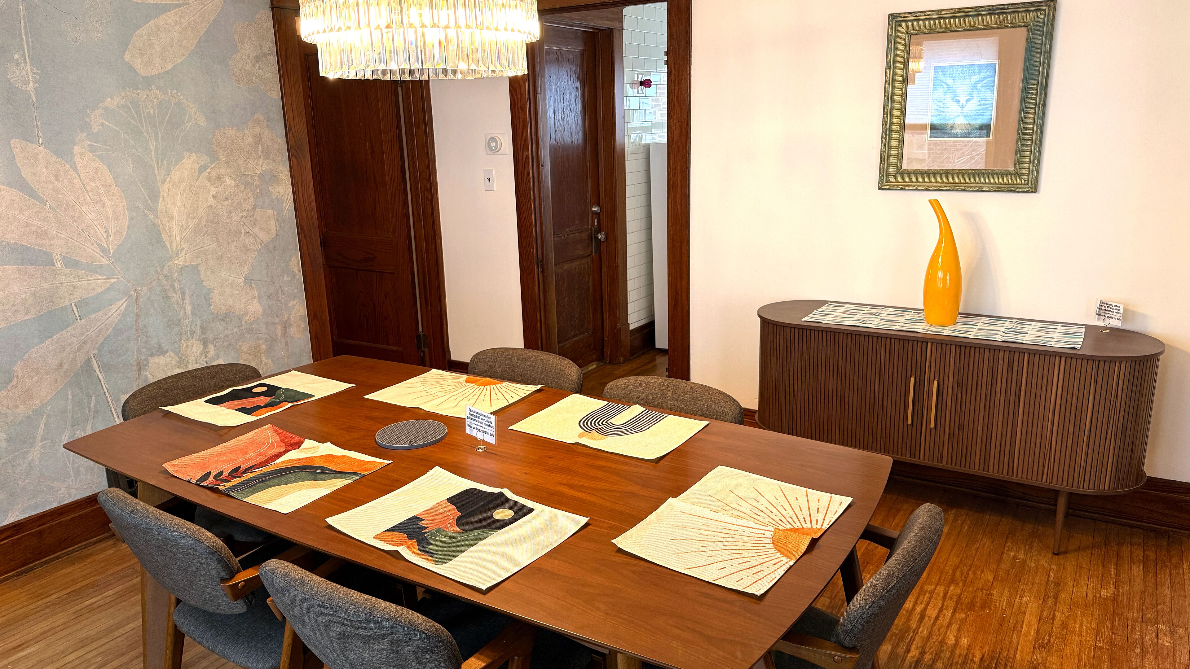 Un salón de conferencias con una mesa de madera, seis sillas y un panel decorativo en la pared.