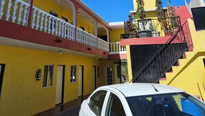 A multi-story building with yellow and red exterior walls, balconies with white railings, and a staircase leading to the upper floors. - Hotel Chalet (Matamoros)