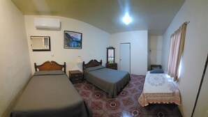A room with two beds, a nightstand, a dresser, an air conditioner, a painting, and a door. - Hotel Chalet (Matamoros)