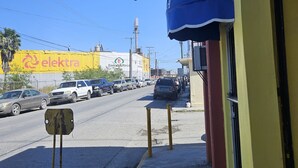 A street view with a yellow building, a blue awning, and a signboard. - Hotel Chalet (Matamoros)