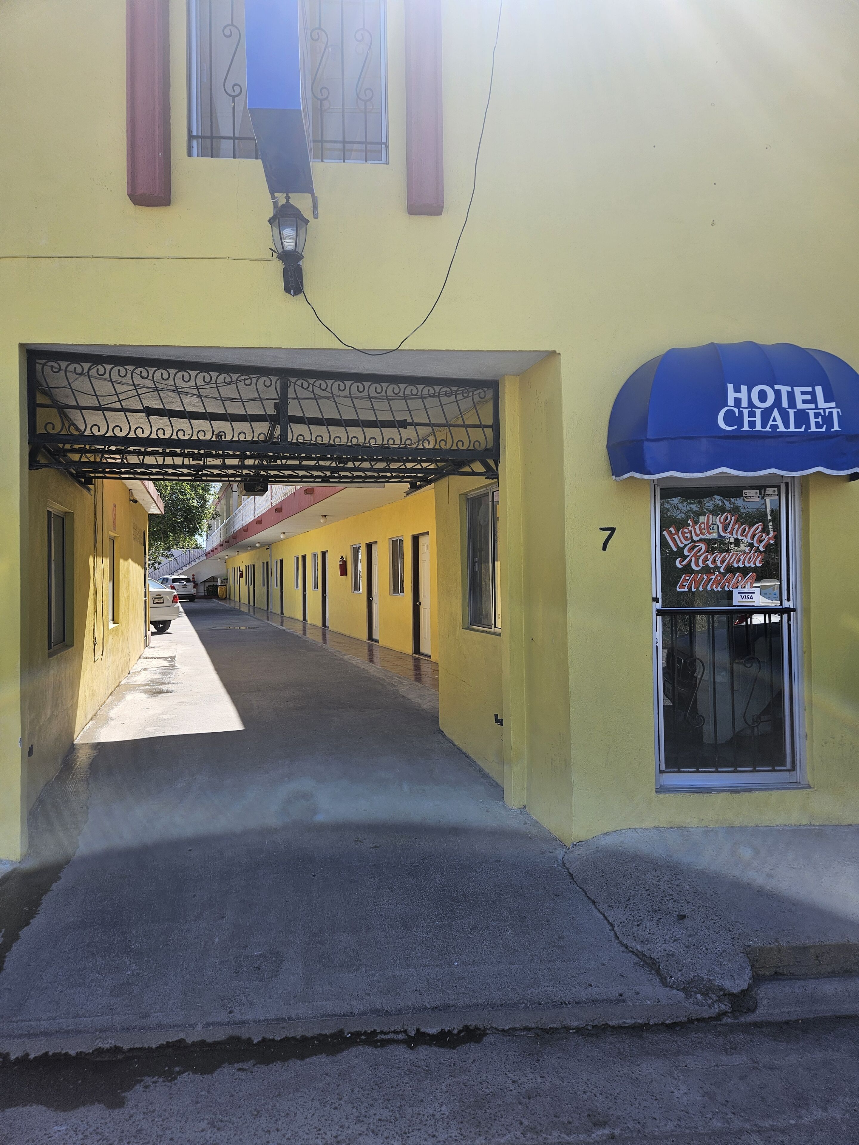 A yellow building with a blue awning labeled "Hotel Chalet" and a sign reading "Hotel Chalet Recogida".