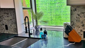 A modern kitchen with a black countertop, a sink, and a window with a green view. - Spacious & Game room in Irving 15 min to Airport& downtown Dallas (Irving)