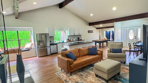 A spacious living area with a brown leather sofa, a matching ottoman, and a kitchen in the background. - Spacious & Game room in Irving 15 min to Airport& downtown Dallas (Irving)