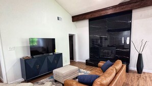 A modern living room with a brown leather sofa, a beige armchair, and a black entertainment unit. - Spacious & Game room in Irving 15 min to Airport& downtown Dallas (Irving)