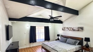 A bedroom with a bed, a ceiling fan, a TV, a nightstand, and a window with curtains. - Spacious & Game room in Irving 15 min to Airport& downtown Dallas (Irving)