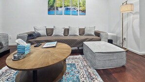 A living room with a sofa, a coffee table, a rug, and a painting on the wall.