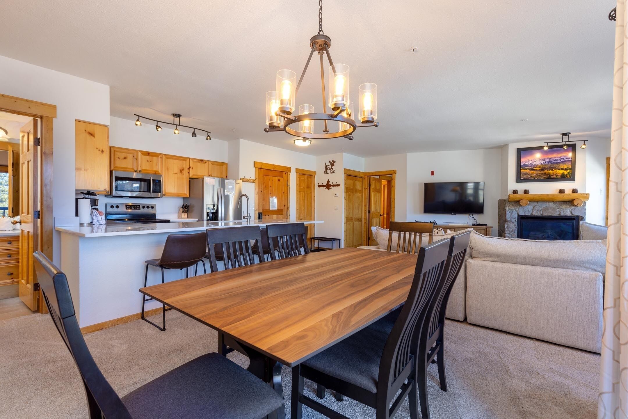 A modern kitchen with wooden cabinets, a central island, and a dining area with a wooden table and chairs.