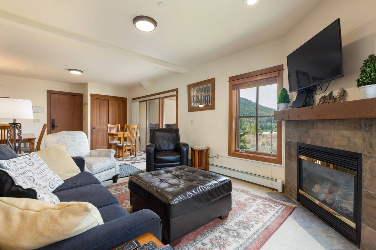 Una sala de estar con chimenea, televisor montado arriba y un ventanal con vistas al exterior.