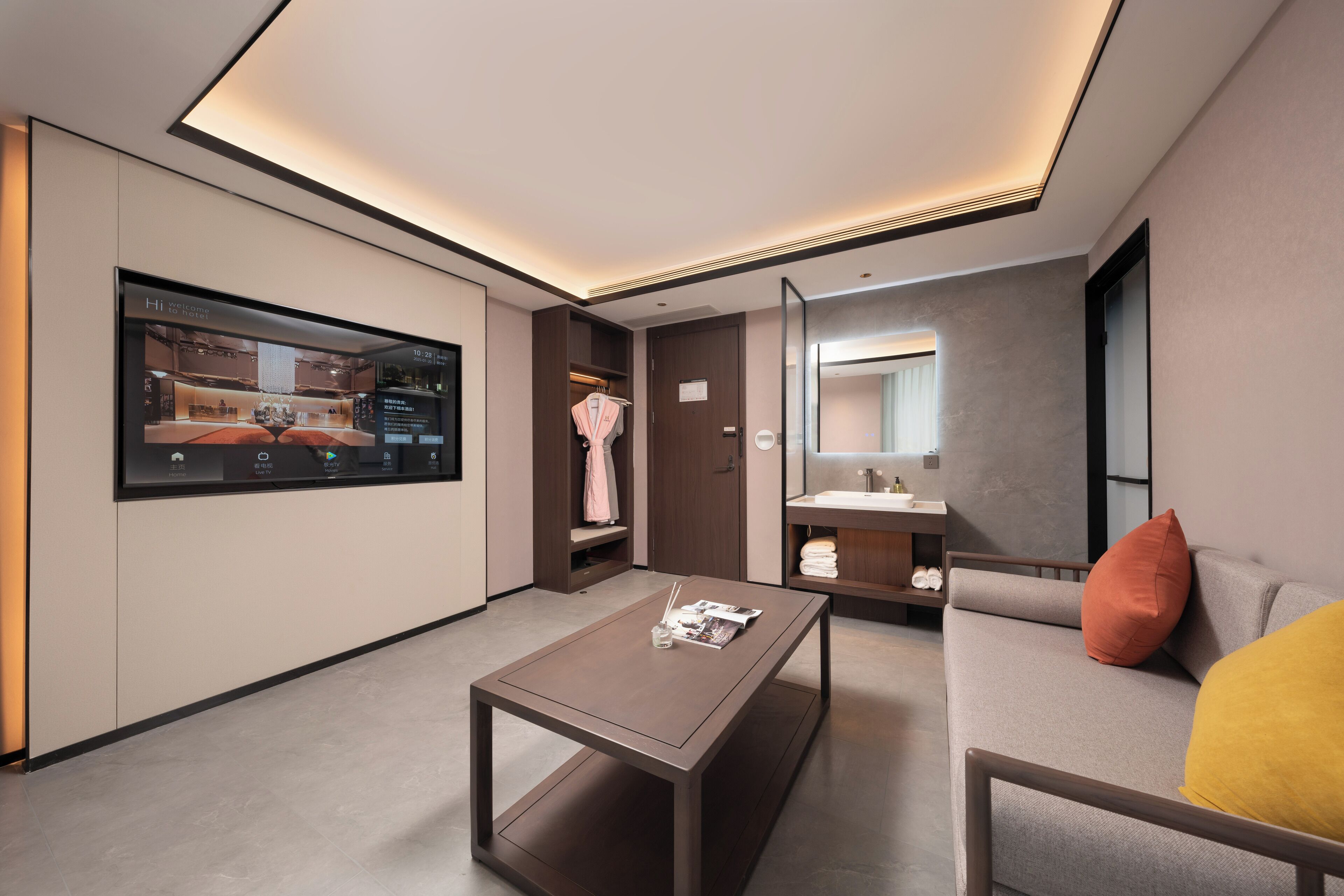 Een moderne hotelkamer met een flatscreen televisie, een bank met kussens, een bijzettafeltje, een spiegel en een kledingkast.