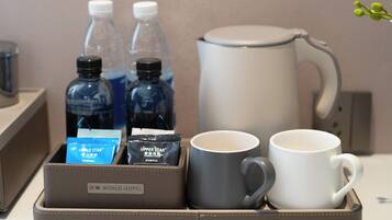 Ontbijttafel in een hotelkamer met een koffiezetapparaat, twee mokken en twee waterflesjes.