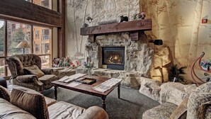 A cozy living room with a stone fireplace, comfortable seating, and a view of the outside. - The Springs & Silver Mill Condos - Keystone Ski Resort CO (Keystone)