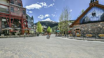 A paved square with outdoor seating, a mountain in the background, and a building with a ski-themed mural.