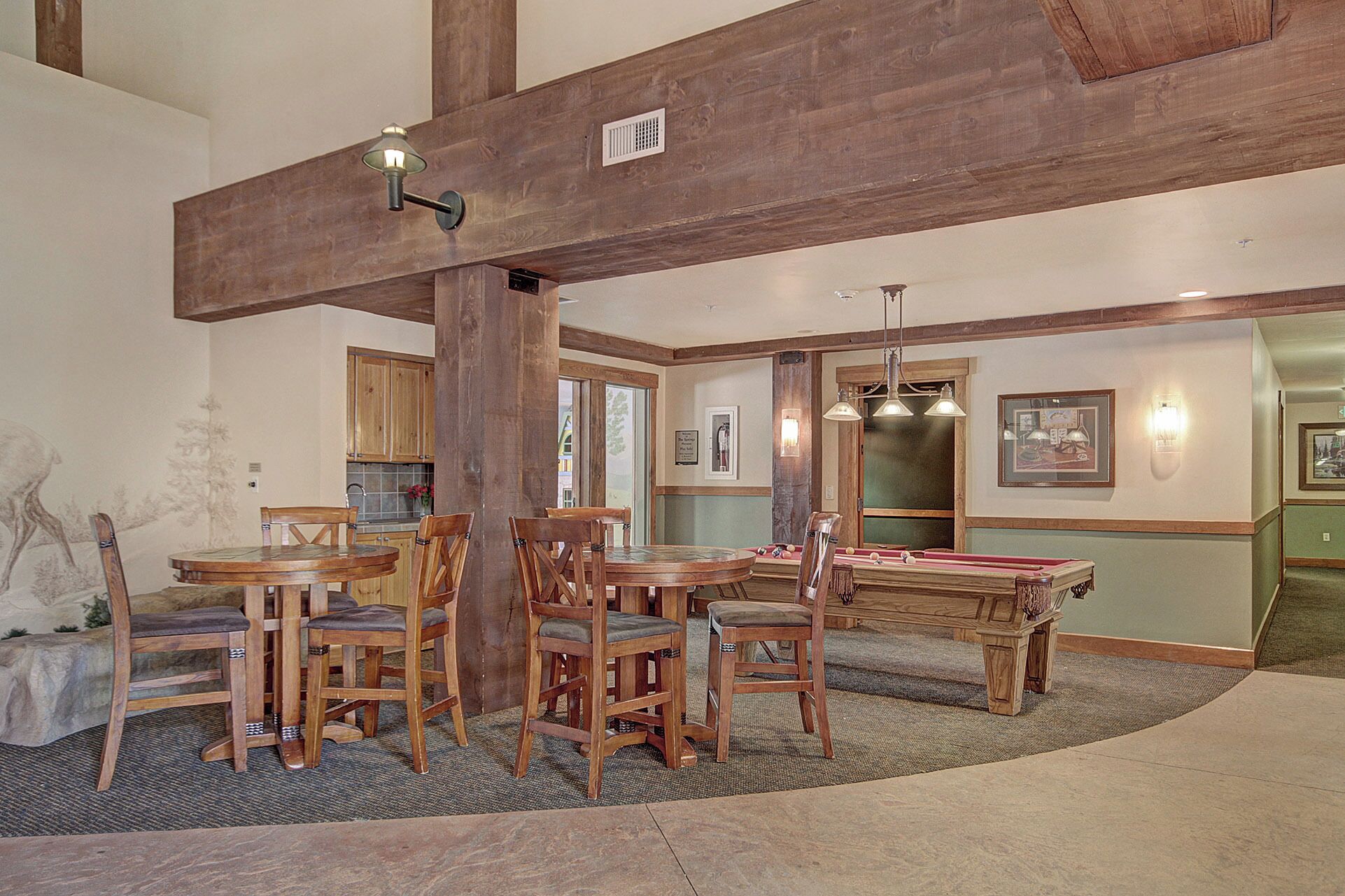 A spacious room with a pool table, wooden chairs, and a dining table.