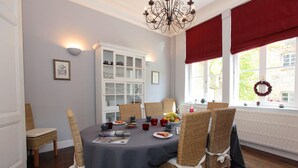 A dining area with a round table, wicker chairs, a chandelier, and a view of the outdoors through large windows. - Spacious, Luxurious, & Cozy Holiday Home - Le Dragon Limbourg (Limbourg)