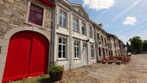 A historic building with a red door and multiple windows, situated on a cobblestone street. - Spacious, Luxurious, & Cozy Holiday Home - Le Dragon Limbourg (Limbourg)