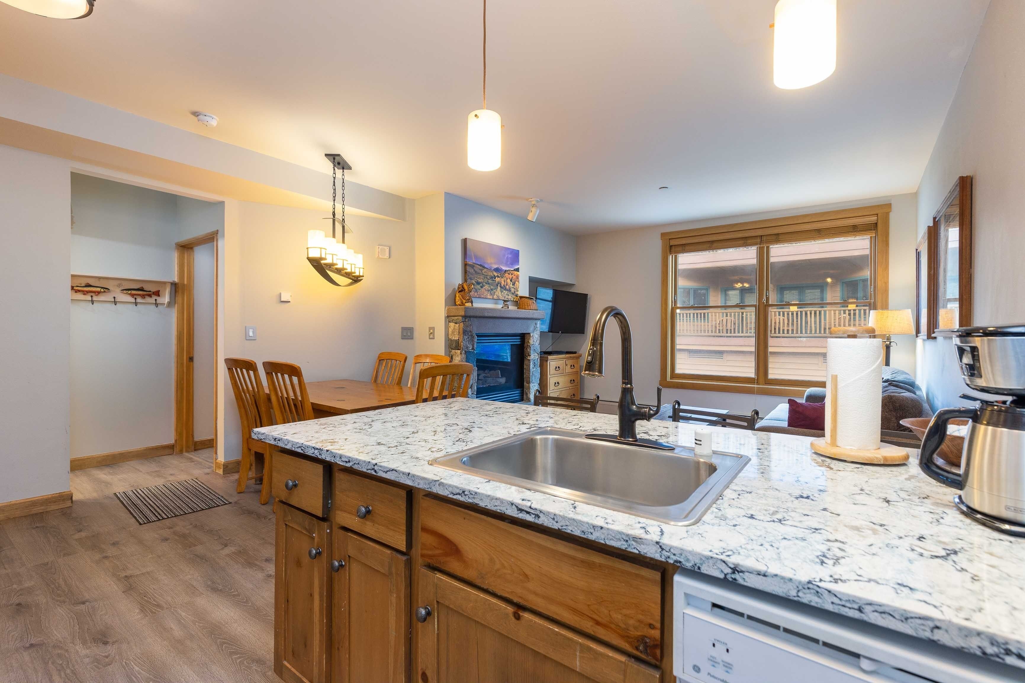 A modern kitchen with granite countertops, wooden cabinets, and a large window overlooking a balcony.
