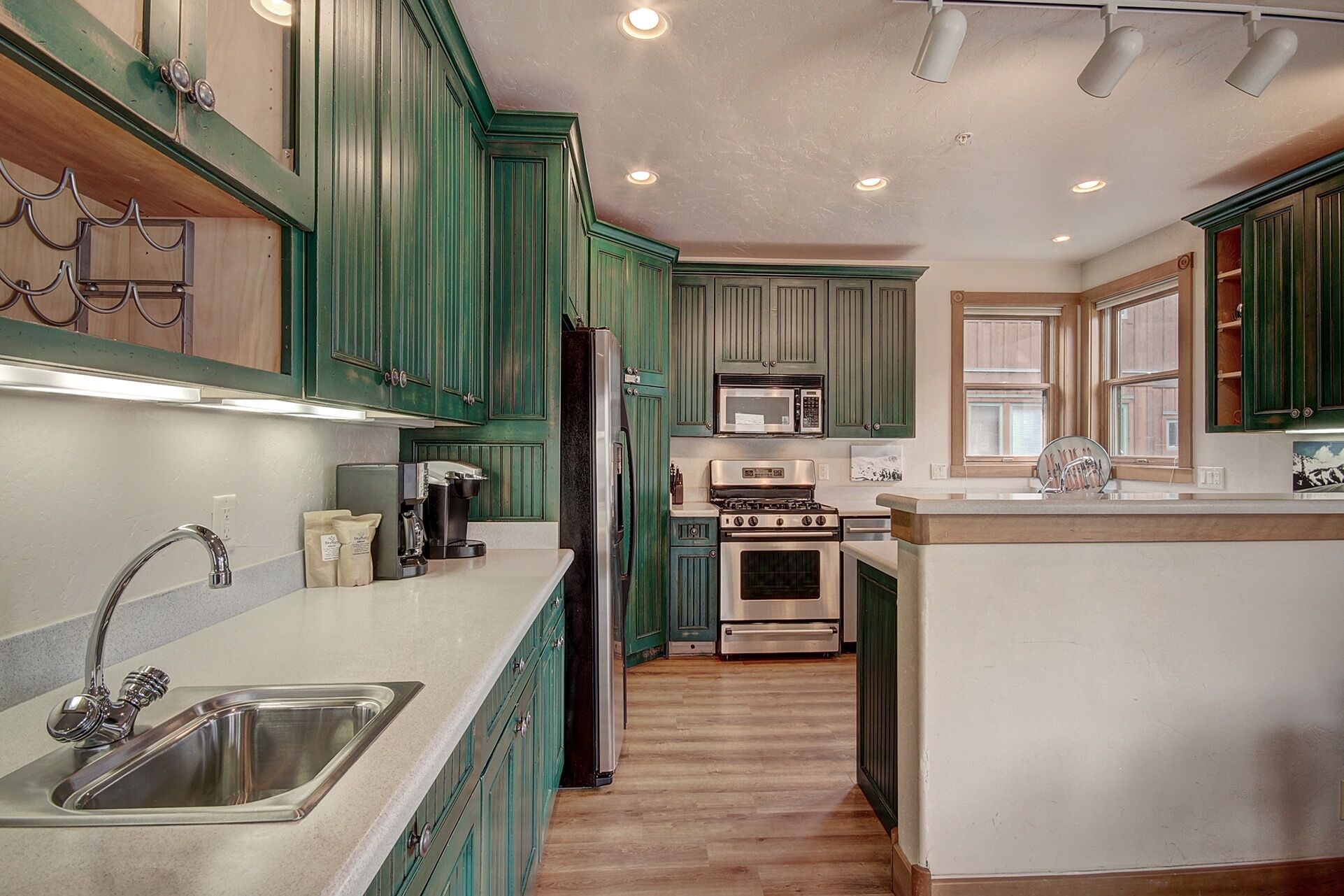 A kitchen with green cabinets, stainless steel appliances, and a central island.