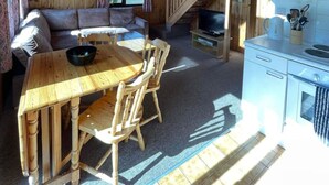 A wooden cabin interior with a dining area, sofa, kitchen, and a staircase. - 3 Bedroom Lodge Lanteglos #21 (Lanteglos)