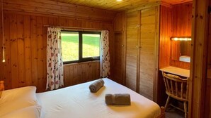 A wooden cabin room with a bed, a desk, and a window. - 3 Bedroom Lodge Lanteglos #21 (Lanteglos)