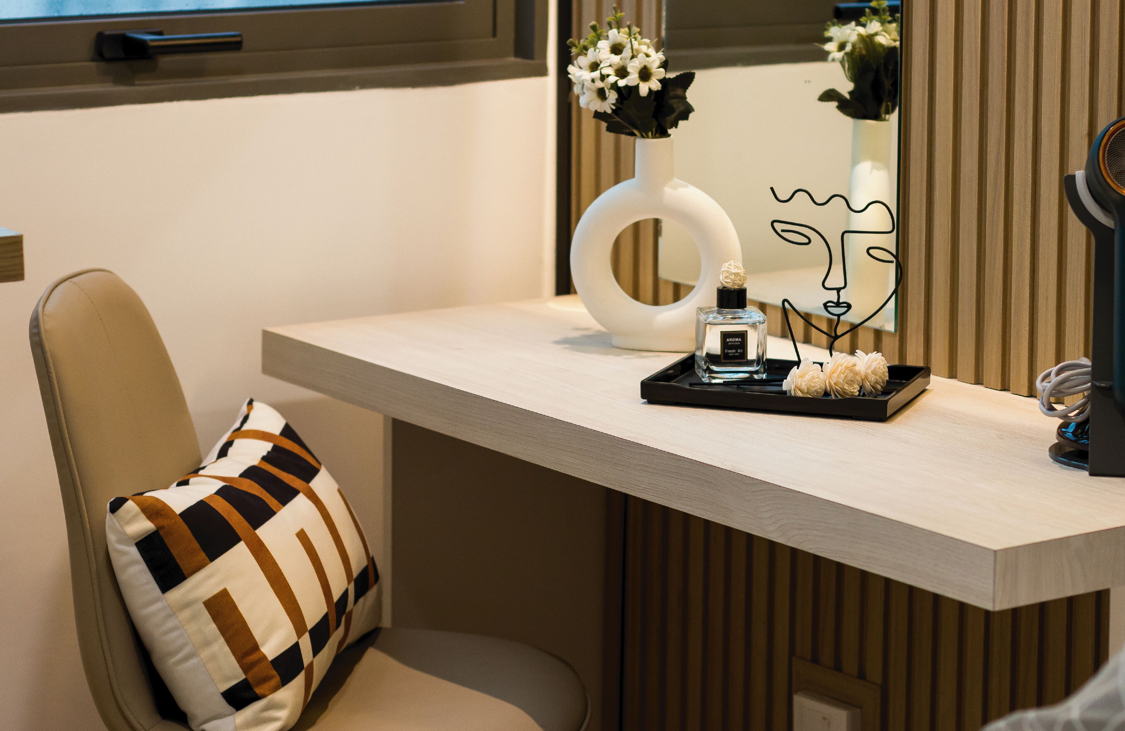 A modern bathroom with a vanity, a mirror, a vase with flowers, and a hairdryer.