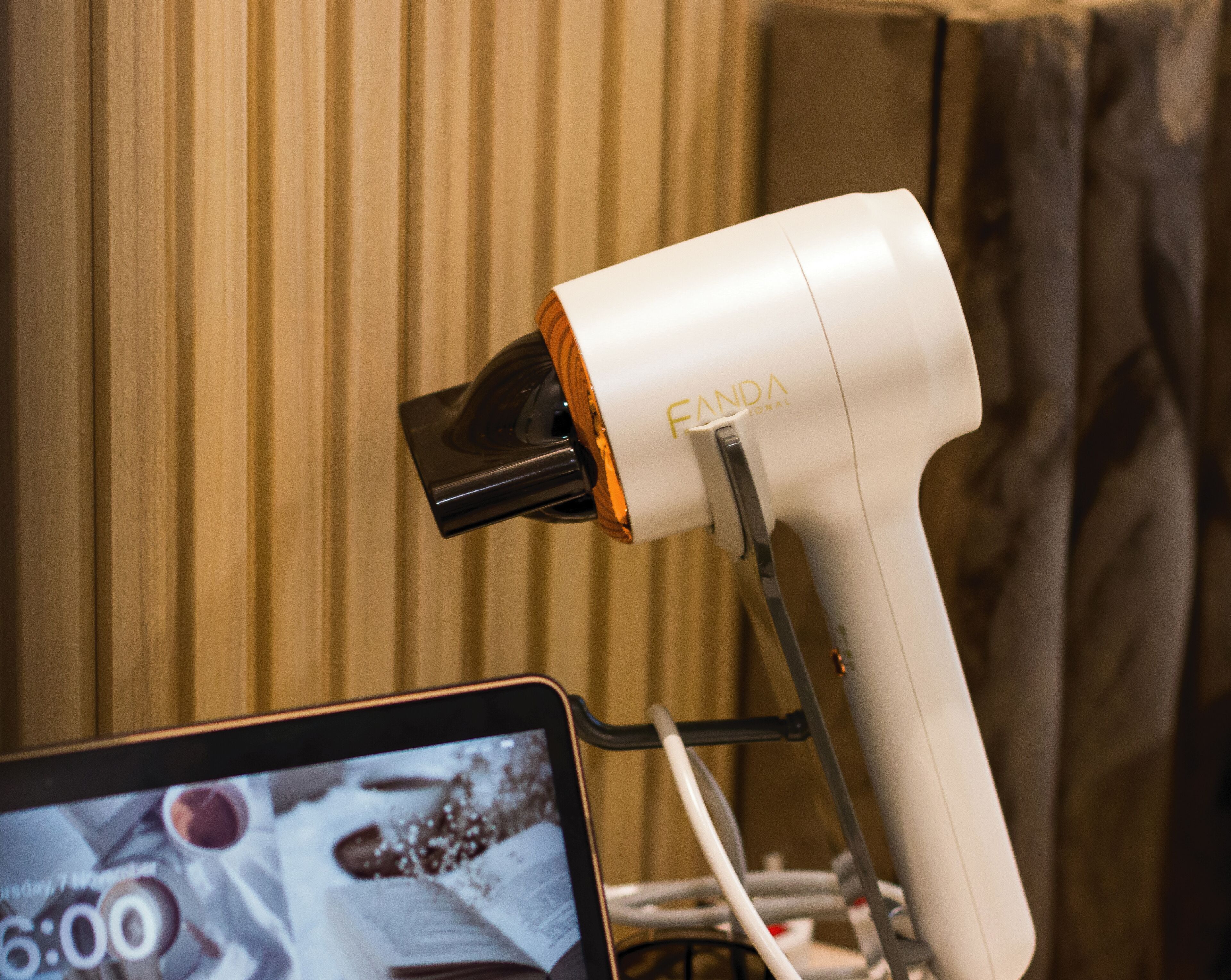 A hair dryer with a wooden accent on a stand, placed against a wooden wall.