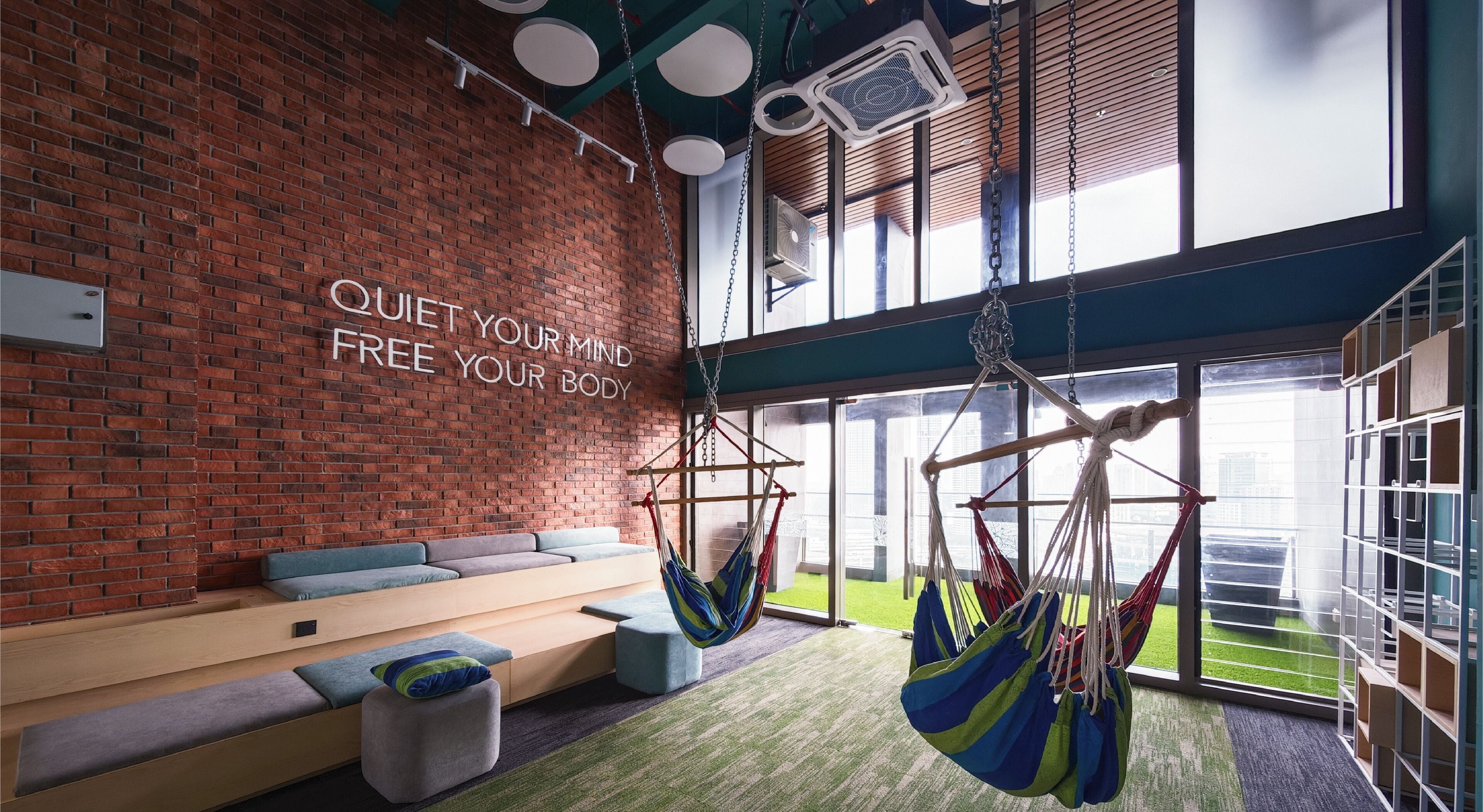 Eine moderne Lounge mit Backsteinwand, einer Hängematte und einer Bank mit Kissen.