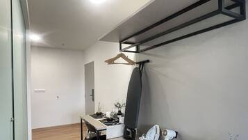Une chambre moderne au design minimaliste, comprenant un bureau avec une chaise, un portant à vêtements et un grand miroir.