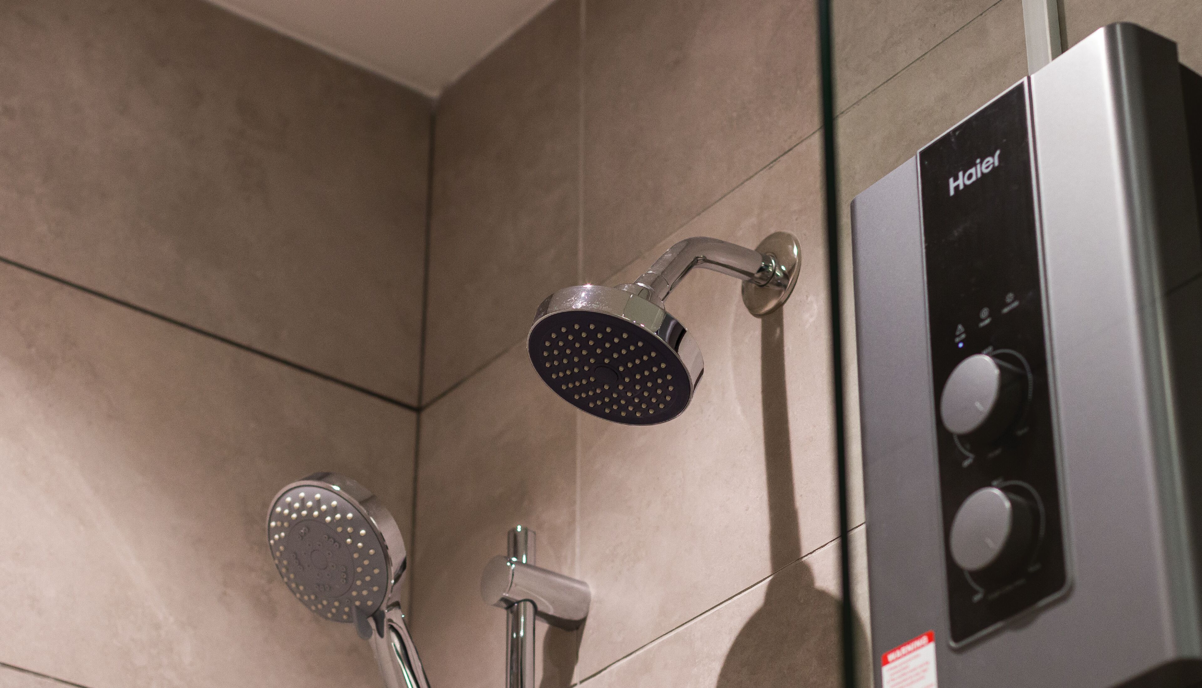 A modern bathroom with a shower head, a handheld shower, and a control panel.