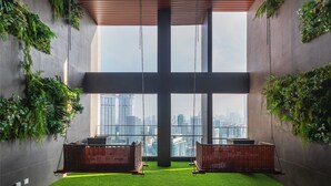 A modern interior with a large cross-shaped window, green walls, and two wicker swings. - The Riv Riveria City KL Sentral (Kuala Lumpur)